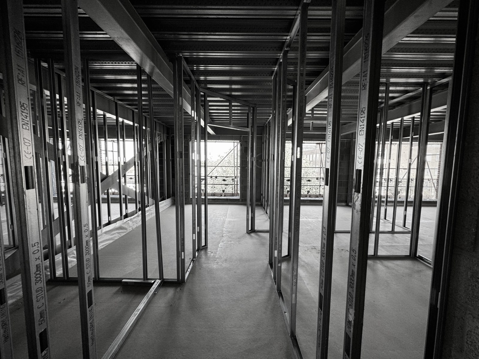 Black and white view of light-gauge SFS steel framing forming apartment partitions inside a conversion
